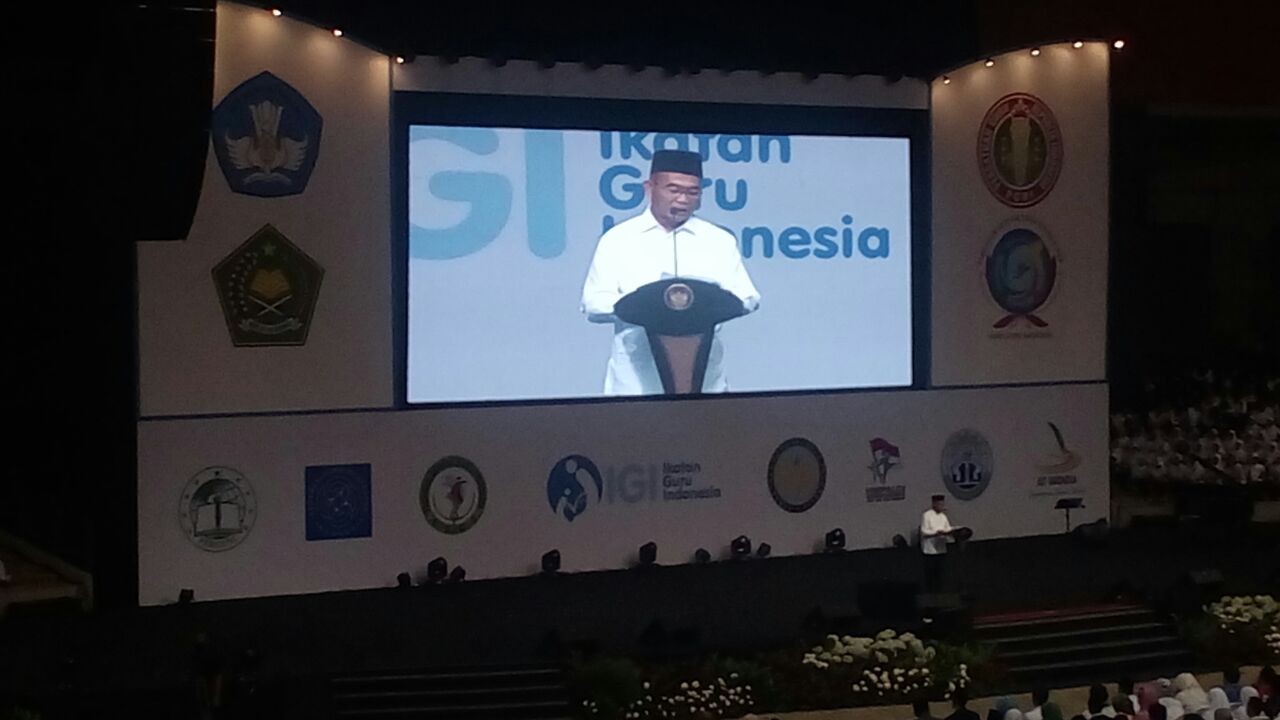 Pidato menteri Pendidikan dan Kebudayaan dalam HGN dengan latar belakang Logo IGI. 